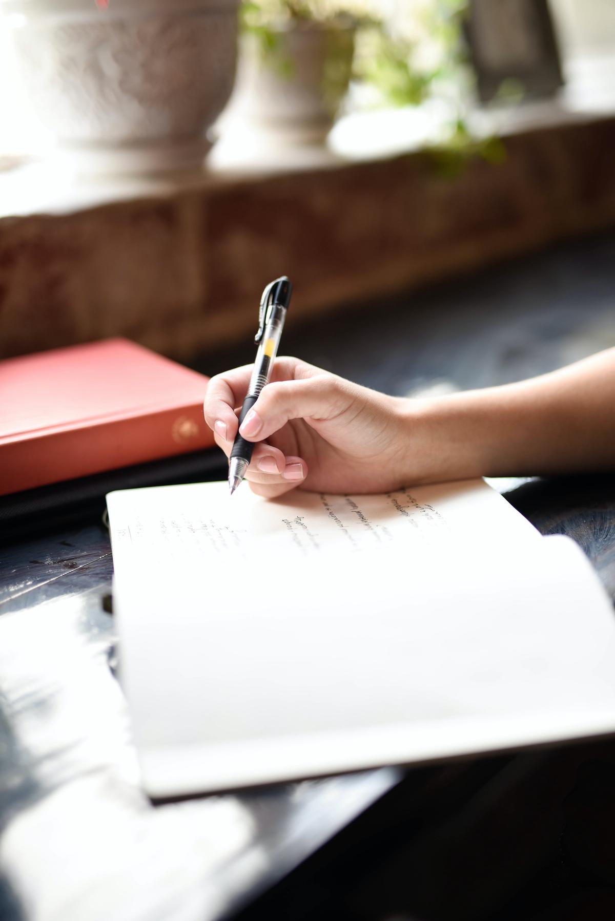 Image illustrating the concept of gratitude and grief, showing a person holding a journal and a picture of a loved one, with both sadness and thankfulness in their expression